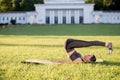 Beautiful young woman lying on a yellow mattress doing pilates or yoga, rolling back intermediate exercises