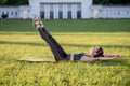 Beautiful young woman lying on a yellow mattress doing pilates or yoga, double leg stretch intermediate exercises