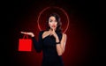 Black friday sale concept for your stor. Shopping girl holding red bag isolated on dark background. Blackfriday holiday