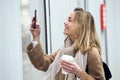 Beautiful young woman making photos of a shop window with mobile on the street Royalty Free Stock Photo