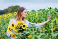 Beautiful young woman making selfie with smartphone on sunflower field with bouquet flowers. Happy woman blogger on Royalty Free Stock Photo