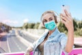 Beautiful young woman with medical face mask and earphones taking a selfie. Coronavirus covid concept. Coronavirus lifestyle