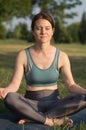 Beautiful young woman meditates in the park at sunset. Woman practices yoga in the park. Yoga in nature Royalty Free Stock Photo