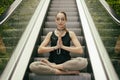 Beautiful Young Woman Meditating on the Escalator with Forest Background, Sitting in Yoga Lotus Posture with Closed Eyes. Str Royalty Free Stock Photo