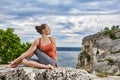 Beautiful young woman meditating in yoga pose at a big river against dramatic sky. Royalty Free Stock Photo