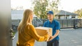 Beautiful Young Woman Meets Delivery Man who Gives Her Cardboard Box Package. Courier Delivering P Royalty Free Stock Photo