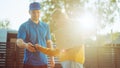 Beautiful Young Woman Meets Delivery Man who Gives Her Cardboard Box Package, She Signs Electronic Royalty Free Stock Photo