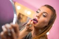 Beautiful young woman with mirror putting on lip liner Royalty Free Stock Photo