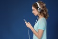 Beautiful young woman with mobile phone listening to music on color background Royalty Free Stock Photo