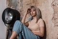 Beautiful young woman model in elegant casual wear posing near a black vintage lamp in the studio. Sexy blonde girl in a Royalty Free Stock Photo