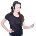 Beautiful young woman model face on cell phone looking up while listening to music in headphones standing against white background Royalty Free Stock Photo