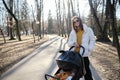 beautiful and young woman mother and baby in a stroller walking Royalty Free Stock Photo