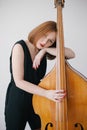 Beautiful woman musician playing on a vintage double bass.