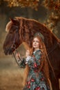 Beautiful young woman in national russian style with red draft horse