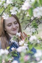 Beautiful young woman near blossoming apple tree enjoys the aroma of flowers. Portrait of girl in the spring garden. Vertical Royalty Free Stock Photo