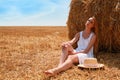 Beautiful young woman near rolled hay bale on sunny day, space for text Royalty Free Stock Photo