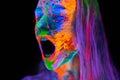 Beautiful young woman in neon light. Portrait of a model with fluorescent makeup who poses in UV light and screams. Royalty Free Stock Photo