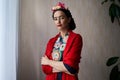 A beautiful young woman with nice makeup looks like Frida Kahlo. Portrait on the background of a regular wall indoors