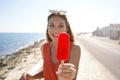 Beautiful young woman offers a popsicle at the camera on summer. Focus on popsicle