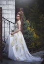 Beautiful woman in an old medieval dress, with a high complex historical hairstyle near the walls of the castle. Royalty Free Stock Photo