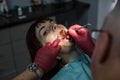 Beautiful young woman with open mouth at dentist having dental treatment at dentist`s office.