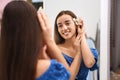 Beautiful young woman with orchid flower looking at herself in large mirror Royalty Free Stock Photo