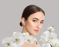 Beautiful young woman and orchid flowers on light background. Spa portrait Royalty Free Stock Photo