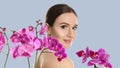 Beautiful young woman and orchid flowers on light background. Spa portrait Royalty Free Stock Photo