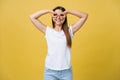 Beautiful young woman over yellow background happy face smiling doing ok or glass sign with hand on eye looking through Royalty Free Stock Photo