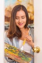 Beautiful young woman painter with color palette and paint brush in hand, in a blurred background Royalty Free Stock Photo