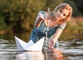 Beautiful young woman with a paper boat by the lake in summertime Royalty Free Stock Photo