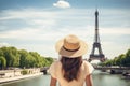 Beautiful young woman in Paris looking at the Eiffel tower, Rear view of woman tourist in sun hat standing in front of Eiffel