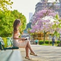 Beautiful young woman in Paris reading on the bench outdoors Royalty Free Stock Photo