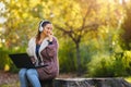 Beautiful young woman in the park using smart phone listening music over headphones Royalty Free Stock Photo