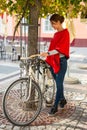 Beautiful young woman parking her bicycle next to a tree