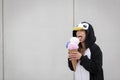 Beautiful, young woman in penguin costume is eating decoration ice cream in front of concrete wall Royalty Free Stock Photo