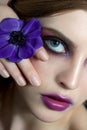 Beautiful young woman with perfect skin, natural make up and flower close to her eye Royalty Free Stock Photo