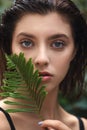 Beautiful young woman with perfect skin and natural make up posing front of plant tropical green leaves background. Teen model Royalty Free Stock Photo