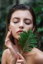 Beautiful young woman with perfect skin and natural make up posing front of plant tropical green leaves background. Teen model Royalty Free Stock Photo