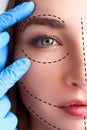 Beautiful young woman with perforation lines on her face before plastic surgery operation. Beautician hands in gloves Royalty Free Stock Photo