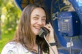 Beautiful young woman in a phone booth. The girl is talking on the phone from the payphone. pretty woman talking by public Royalty Free Stock Photo