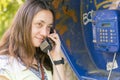 Beautiful young woman in a phone booth. The girl is talking on the phone from the payphone. pretty woman talking by public Royalty Free Stock Photo