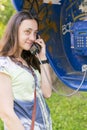 Beautiful young woman in a phone booth. The girl is talking on the phone from the payphone. woman talking by public telephone Royalty Free Stock Photo