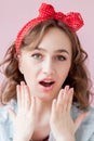 Beautiful young woman with pin-up make-up and hairstyle. Studio shot on pink background Royalty Free Stock Photo