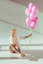 beautiful young woman in pink bra holding pink balloons while sitting Royalty Free Stock Photo