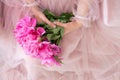 Beautiful young woman in pink dress holding peony flowers bouquet in her hands Royalty Free Stock Photo