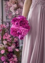 Beautiful young woman in pink dress holding peony flowers bouquet in her hand Royalty Free Stock Photo