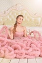 Portrait of beautiful young woman in pink dress posing in bedroom