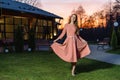 A beautiful young woman in pink dress walks towards the camera, Model dress, sunset light. Royalty Free Stock Photo