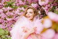 Beautiful young woman in pink glamour dress with smiling face in spring flowers bloom park Royalty Free Stock Photo